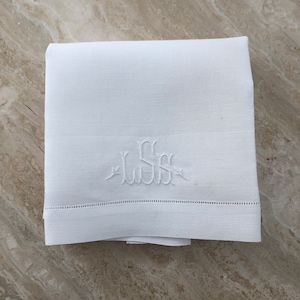 May include: White linen hand towel with a monogrammed "JSS" embroidered in the center.