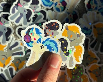 May include: A collection of die-cut stickers featuring cartoon ponies with holographic star and sparkle effects. The stickers display various pony characters in different colors, including blue, orange, and dark gray, with musical note symbols.
