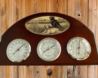 Estación meteorológica VTG con barómetro, termómetro e higrómetro, base de madera con diseño de perros de laboratorio y llave.