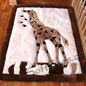 Könnte beinhalten: Ein weißer und brauner Plüschteppich mit einem Giraffenmuster. Die Giraffe ist aus braunem und schwarzem Fell gefertigt und steht auf ihren Hinterbeinen. Der Teppich hat einen braunen Rand.