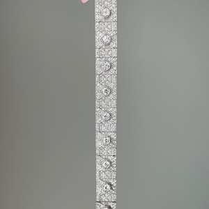 K&ouml;nnte beinhalten: Ein silbernes Armband mit geometrischem Design, besetzt mit funkelnden Diamanten.