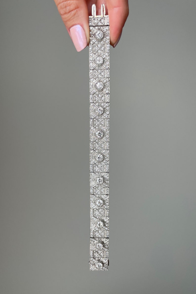 K&ouml;nnte beinhalten: Ein silbernes Armband mit geometrischem Design, besetzt mit funkelnden Diamanten.