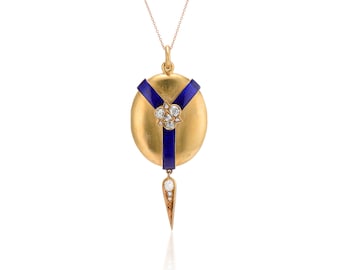 May include: A gold pendant necklace. The round, textured gold locket has blue enamel stripes and a diamond cluster. A diamond-studded, teardrop-shaped charm hangs below. The necklace chain is gold. The pendant is a vintage design.