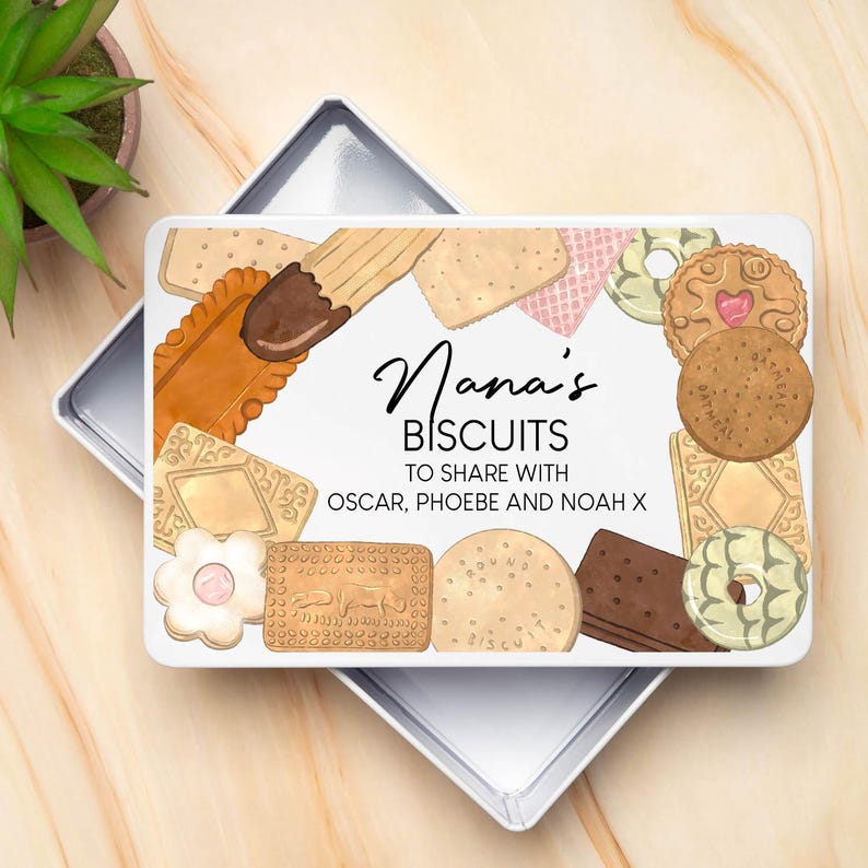 Op de afbeelding: Een witte rechthoekige koektrommel met een verscheidenheid aan koekjes rond de rand. De trommel heeft de woorden "Nana's BISCUITS TO SHARE WITH OSCAR, PHOEBE AND NOAH X" in zwart script.