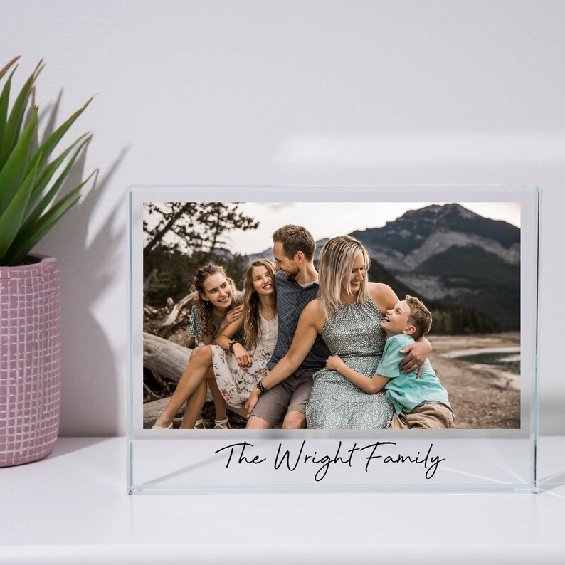 May include: A glass photo frame with a picture of a family of five in front of a mountain range. The text "The Wright Family" is inscribed on the bottom of the frame.