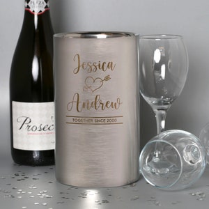 Puede incluir: Un enfriador de vino de acero inoxidable plateado con una inscripci&oacute;n personalizada que dice "Jessica & Andrew Together Since 2000" con un coraz&oacute;n y una flecha.