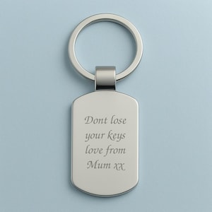 Könnte beinhalten: Rechteckiger Schlüsselanhänger in Silber mit einem Ring oben. Der Schlüsselanhänger hat den eingravierten Text: "Dont lose your keys love from Mum xx". Der Hintergrund ist hellblau.