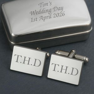 Könnte beinhalten: Silberne Manschettenknöpfe in rechteckiger Form mit den eingravierten Initialen "T.H.D.". Die Manschettenknöpfe werden in einer silbernen Geschenkbox mit dem eingravierten Text "Tim's Wedding Day 1st April 2026" geliefert.