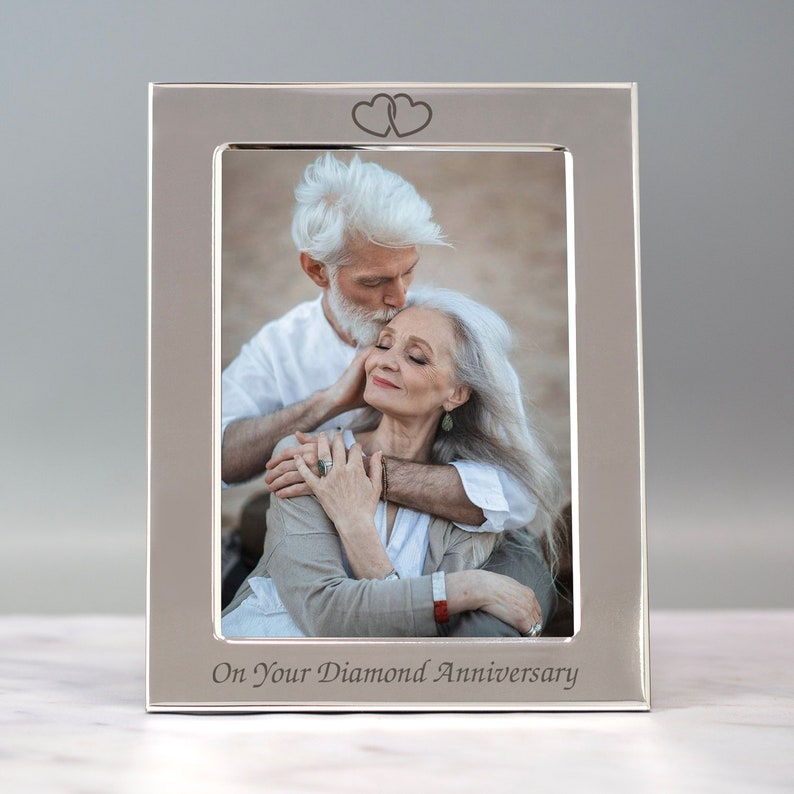 Op de afbeelding: Zilveren fotolijst met een stel op een foto. De lijst is bovenaan gegraveerd met twee harten en onderaan met de woorden "On Your Diamond Anniversary".