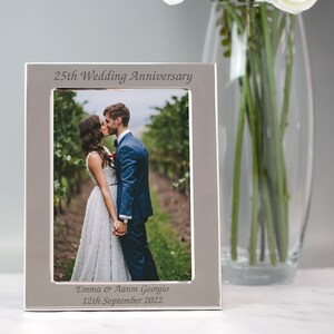 May include: Silver photo frame with a picture of a couple kissing. The frame is engraved with "25th Wedding Anniversary", "Emma & Aaron Georgio", and "12th September 2022".