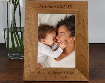 May include: A wooden photo frame with a light brown finish. The frame has a photo of a mother and child inside. The frame is engraved with the text "Mummy and Me" and "Our first Mother's Day! Love Arlow X".