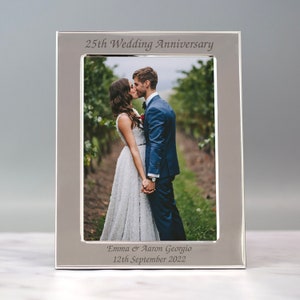 May include: Silver photo frame with a picture of a couple kissing. The frame has the text "25th Wedding Anniversary" and "Emma & Aaron Georgio 12th September 2022" engraved on it.