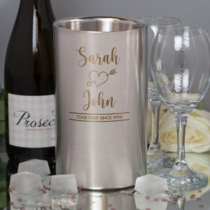 Puede incluir: Enfriador de vino de acero inoxidable plateado con una inscripci&oacute;n dorada que dice "Sarah & John Together Since 1996" con un coraz&oacute;n y una flecha.