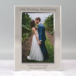 May include: Silver photo frame with a picture of a couple kissing. The frame is engraved with "25th Wedding Anniversary", "Emma & Aaron Georgio", and "12th September 2022".