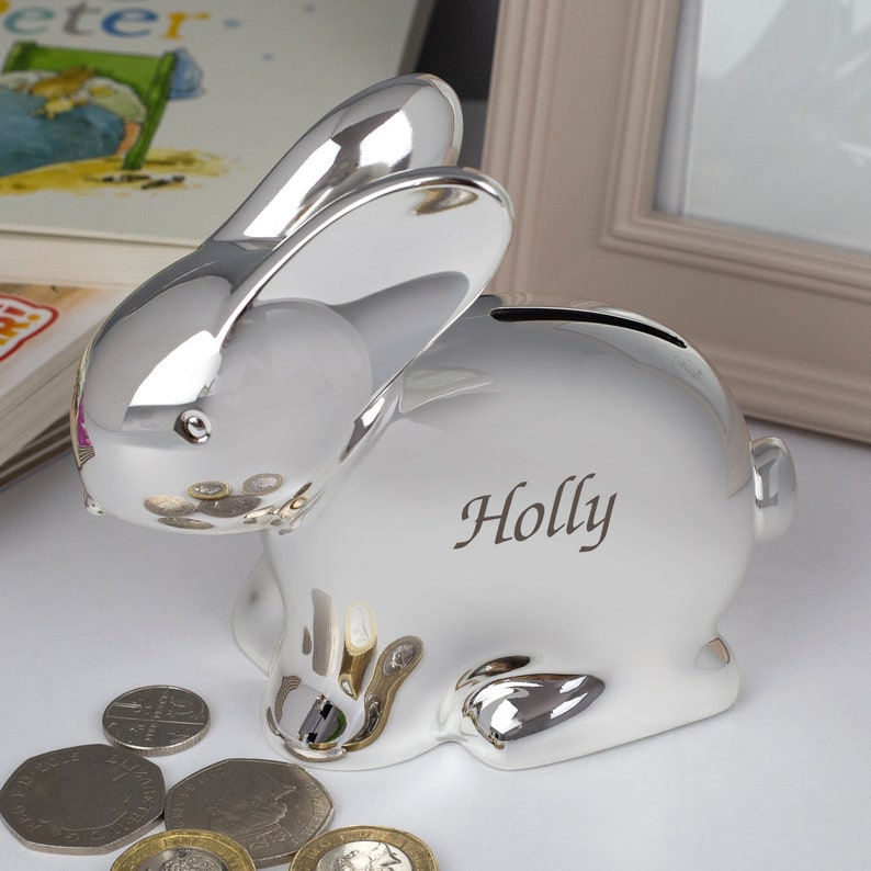 May include: Silver bunny shaped piggy bank with the name "Holly" engraved on the side.