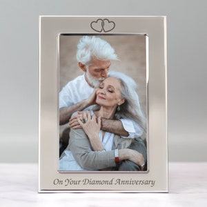 Op de afbeelding: Zilveren fotolijst met een foto van een ouder koppel dat elkaar omhelst. De lijst heeft bovenaan twee in elkaar verweven harten en onderaan de inscriptie "On Your Diamond Anniversary".