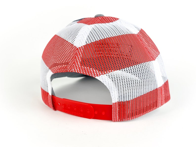 May include: A red, white, and blue trucker hat with a mesh back. The hat has a gray brim and a red strap.