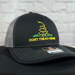 May include: A black and gray trucker hat with a yellow embroidered snake and the text "DONT TREAD ON ME".