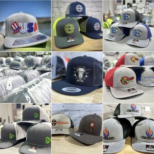 May include: A collection of various embroidered baseball caps with different designs and logos. The caps are in a variety of colors, including gray, black, blue, red, and green. Some of the logos include "USA", "Fire Dept", "Power Air Mechanical", and "SMC".