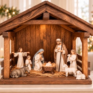 May include: A wooden nativity set featuring figurines of Mary, Joseph, the infant Jesus in a manger, an angel, a child, a donkey, and two sheep. The figures are arranged inside a dark brown wooden stable structure with a gabled roof.