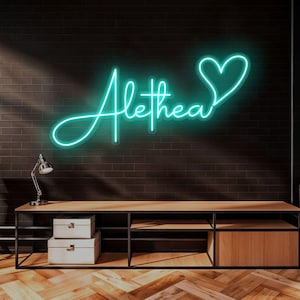 May include: A teal neon sign displaying the name "Alethea" in a cursive font, with a heart symbol at the end. The sign is mounted on a dark brick wall above a wooden console with storage boxes and a desk lamp.
