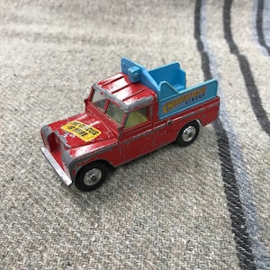 May include: A red toy truck with a blue bed and the words "Chipperfield's Circus" on the side. The truck has a yellow sticker on the side that says "The Circus is Here".