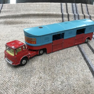 May include: A red toy truck with a blue and red trailer. The trailer has the words "Sheffields Circus" printed on the side.