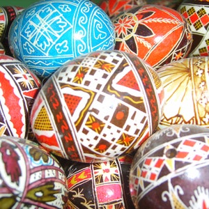 May include: A collection of intricately decorated Easter eggs with various geometric and floral patterns in shades of red, blue, black, white, and gold.