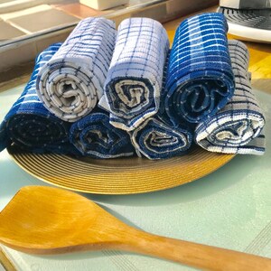 May include: A set of six blue and white striped kitchen towels rolled up and arranged on a gold-colored plate. The towels are made of a soft, absorbent fabric and are perfect for drying dishes, hands, and surfaces.