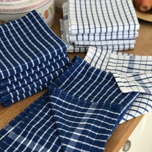 May include: A stack of blue and white checkered kitchen towels, folded and arranged on a wooden surface.