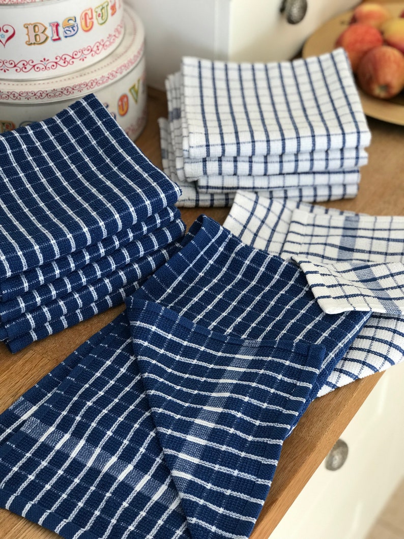 May include: A stack of blue and white checkered kitchen towels, folded and arranged on a wooden surface.