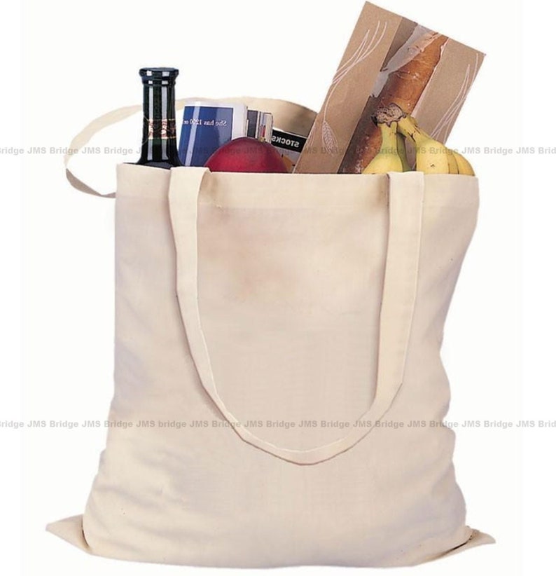 May include: A white canvas tote bag with two handles, filled with groceries including a bottle of wine, a loaf of bread, bananas, and a magazine.