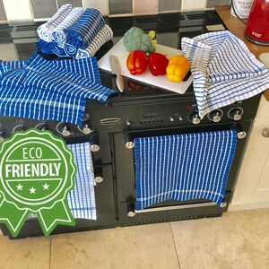 May include: A set of blue and white checkered kitchen towels with the words "Eco Friendly" on a green label. The towels are hanging on a black range.