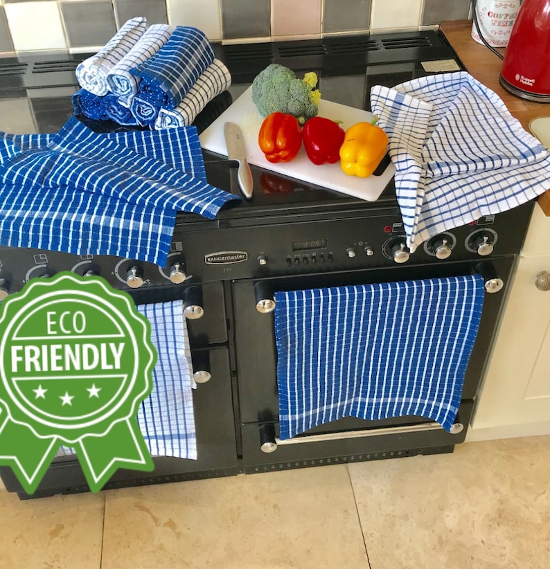 May include: A set of blue and white checkered kitchen towels with the words "Eco Friendly" on a green label. The towels are hanging on a black range.