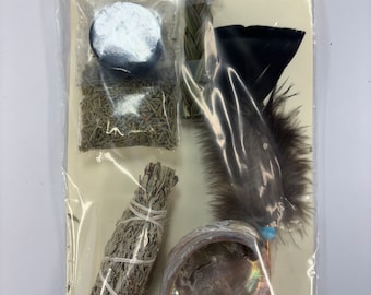 May include: A kit containing various items for smudging rituals, including sweetgrass, sage bundle, flat cedar, abalone shell, quick-lite charcoal, and a mini fan. The kit is packaged in a clear plastic bag with a white label that reads "Yellowstone Pawn & Trade".