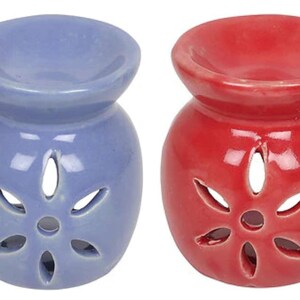May include: Two ceramic oil diffusers, one periwinkle blue and one red. Each has a round base with a flower-shaped cutout and a bowl-shaped top. The diffusers are designed for aromatherapy.
