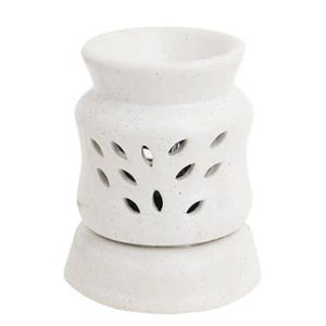 Puede incluir: Un difusor de aceites esenciales de cerámica blanca con acabado moteado. El difusor tiene una base redondeada y un cuerpo cilíndrico con cortes en forma de hoja. La parte superior tiene una amplia abertura.