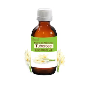 May include: A brown glass bottle with a white cap, labeled "Bangoia Pure & Natural Tuberose Essential Oil". White tuberose flowers are arranged around the bottle.
