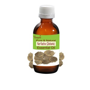 Könnte beinhalten: Eine braune Glasflasche mit weißem Verschluss, beschriftet mit "Bangoia Pure & Natural Nar Kachur (Zedoaria) Essential Oil". Die Flasche ist von getrockneten, braunen, runden Wurzelstücken umgeben.