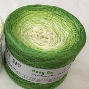 May include: A skein of green and white ombre yarn labeled "Hang On" with the text "200g Lauflange ca 380m - 50% Baumwolle" on the label.