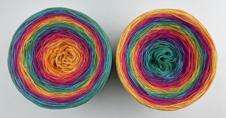 May include: Two skeins of rainbow colored yarn wound into balls. The yarn is a gradient of yellow, orange, red, purple, blue, green, and yellow.