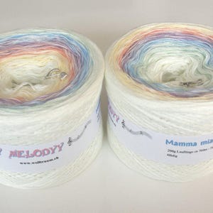 May include: Two skeins of yarn, one labeled "My Melody" and the other "Mamma mia". Both skeins are white with a rainbow of colors woven into the yarn.