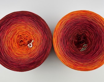 May include: Two skeins of ombre yarn in shades of red, orange, and yellow. The yarn is wound into balls and has a textured appearance.