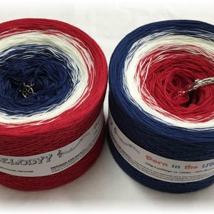 May include: Two skeins of yarn in red, white, and blue colorways. The skein on the left is labeled "Melody" and the skein on the right is labeled "Born in the USA".