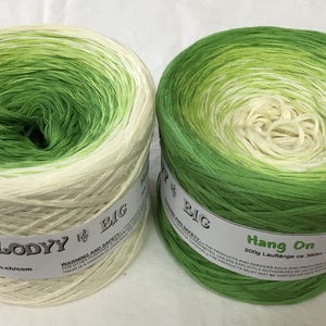 May include: Two skeins of green and white ombre yarn. The skein on the left is labeled "Melody Big" and the skein on the right is labeled "Hang On 200g Laufl&auml;nge ca 380m."