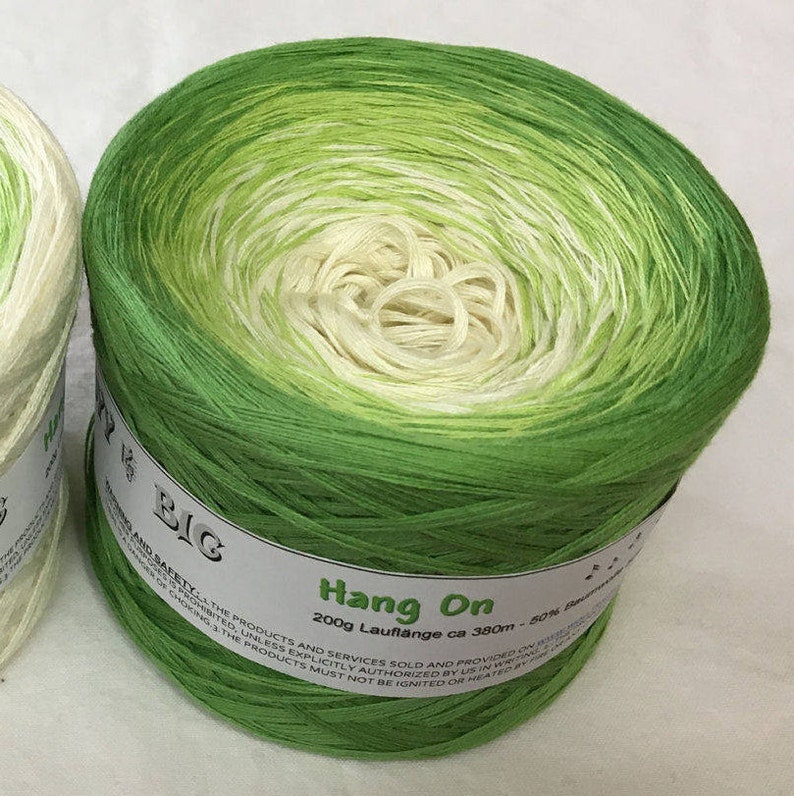 May include: A skein of green and white ombre yarn labeled "Hang On" with the text "200g Lauflange ca 380m - 50% Baumwolle" on the label.