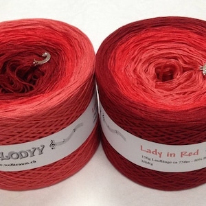 May include: Two skeins of red yarn, one labelled "Melody" and the other "Lady in Red". Both skeins are ombre, transitioning from a lighter red to a darker red.