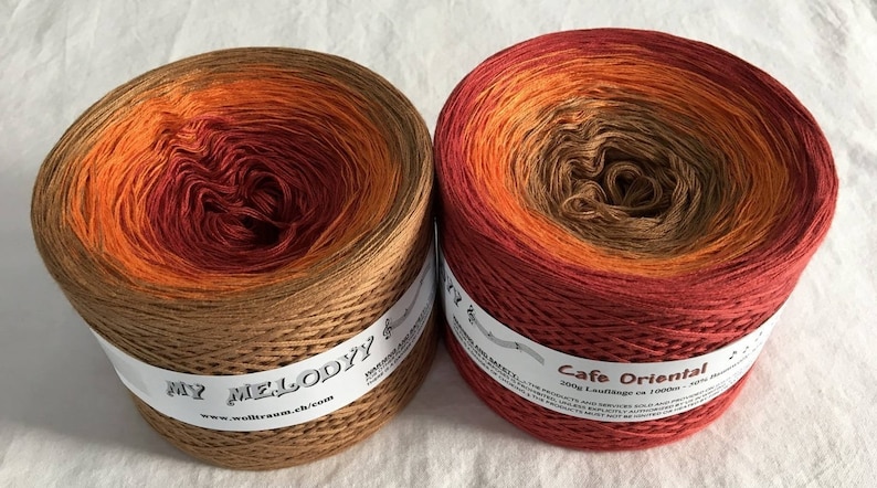 May include: Two skeins of ombre yarn in shades of brown, orange, and red. The skeins are labeled "My Melody" and "Cafe Oriental".