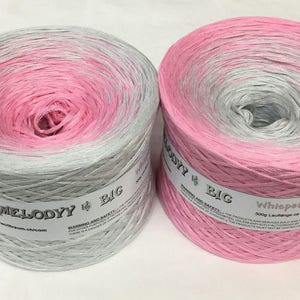 May include: Two skeins of ombre yarn, one in pink and grey and the other in grey and pink. The yarn is labeled "My Melody # Big" and "Whisper 300g Laufl&auml;nge ca. 570m."
