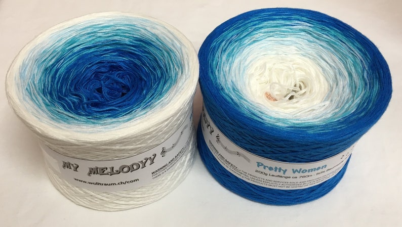 May include: Two skeins of yarn in a gradient colorway of white to blue. The skein on the left is labeled "My Melody" and the skein on the right is labeled "Pretty Women".